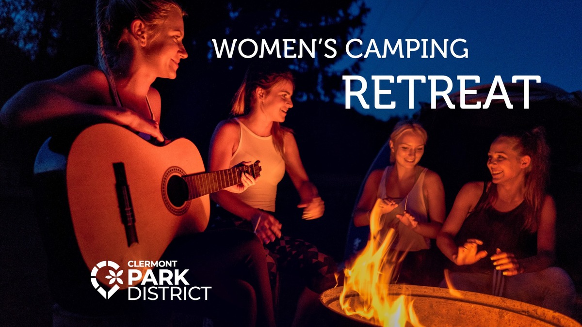 Four women are pictured sitting around a campfire with the words "Women's Camping Retreat" in the top left corner. The woman closest to the camera is holding a guitar. All four are smiling.